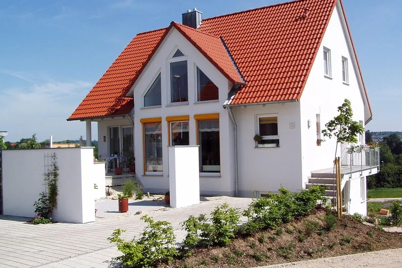 Neu gebautes Einfamilienhaus mit rotem Ziegeldach und Garten